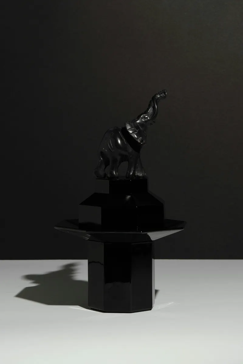 Black sculptural figurine on a geometric pedestal